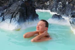A woman enjoys spa in hot spring Blue Lagoon in Iceland